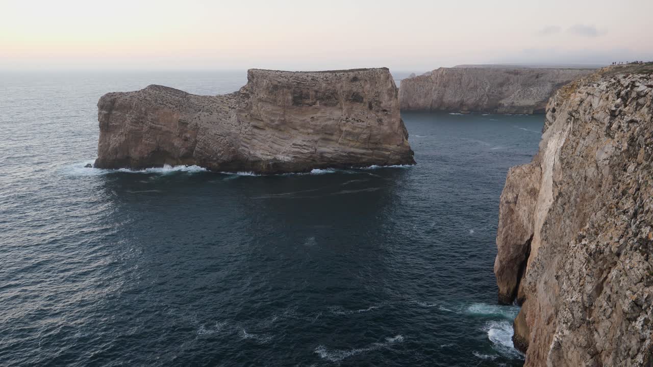 Establishing shot, Scenic view of a wave hitting the Rock formation near the shoreline of Algarve, Portugal, Cloudy misty sky in the background