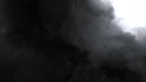 4k espeso humo negro ondulando de la quema de la fogata pan hacia arriba