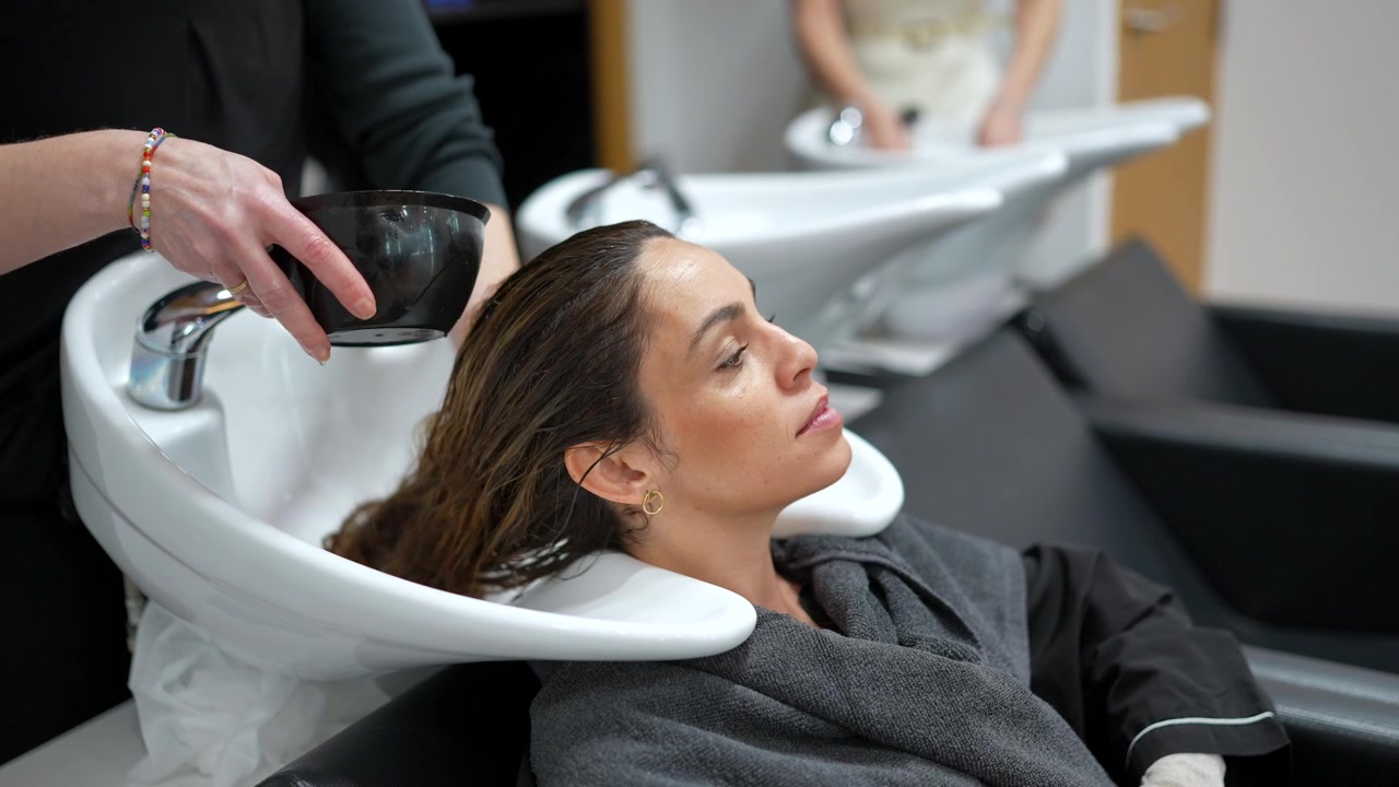 Parrucchiere che sciacqua i capelli di una donna in salone