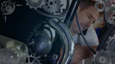 animación de girar los engranajes sobre un mecánico caucásico arreglando una motocicleta y hablando en un teléfono inteligente
