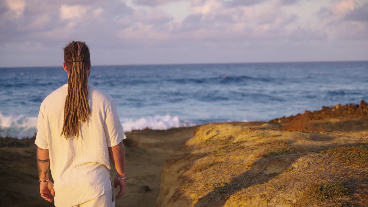Man with dreadlocks on a beach at sunset