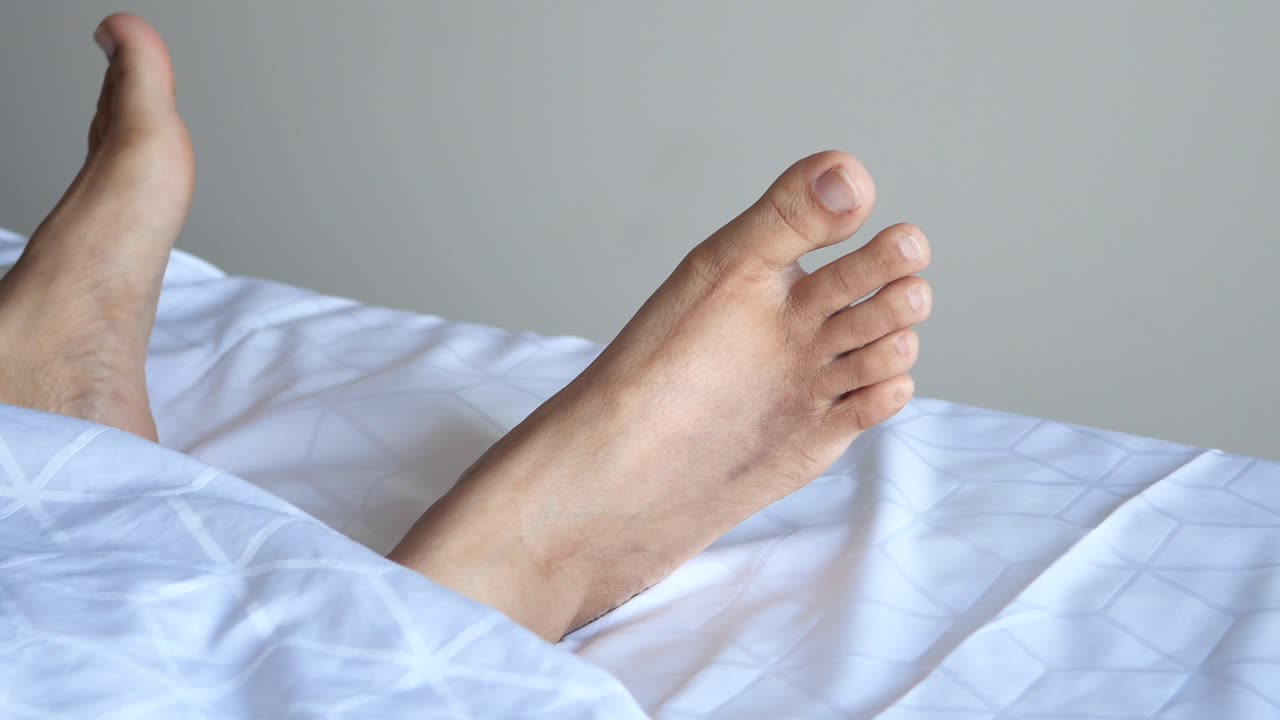 Close-up of a Person's Feet Resting on a Bed