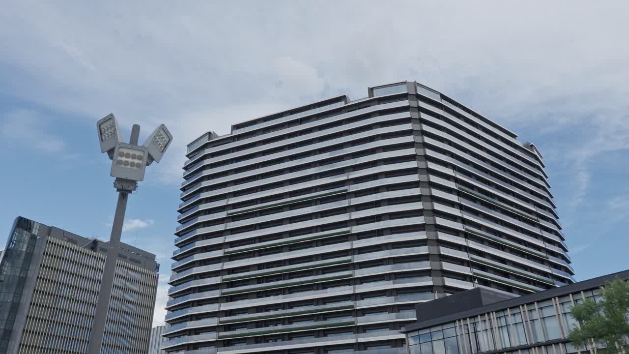 A modern multi-story building and a contemporary street light against a cloudy sky in an urban area