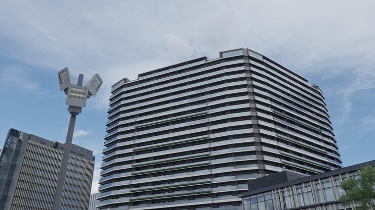 Un moderno edificio a più piani e un lampione stradale contemporaneo contro un cielo nuvoloso in un'area urbana.