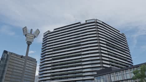 a modern multi-story building and a contemporary street light against a cloudy sky in an urban area