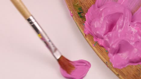 painting the color pink with a paintbrush on a piece of paper