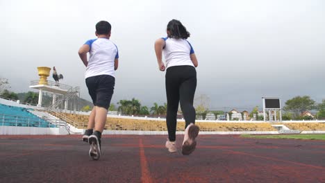 back view of boy and girl running on the track