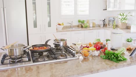 general view of kitchen and frying pan with vegetables on table