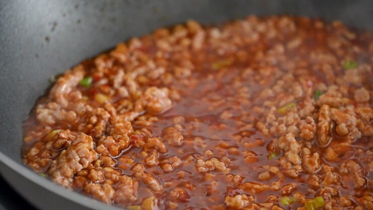 Stir-frying ground pork with hot spicy sauce when cooking mapo tofu cuisine at home.