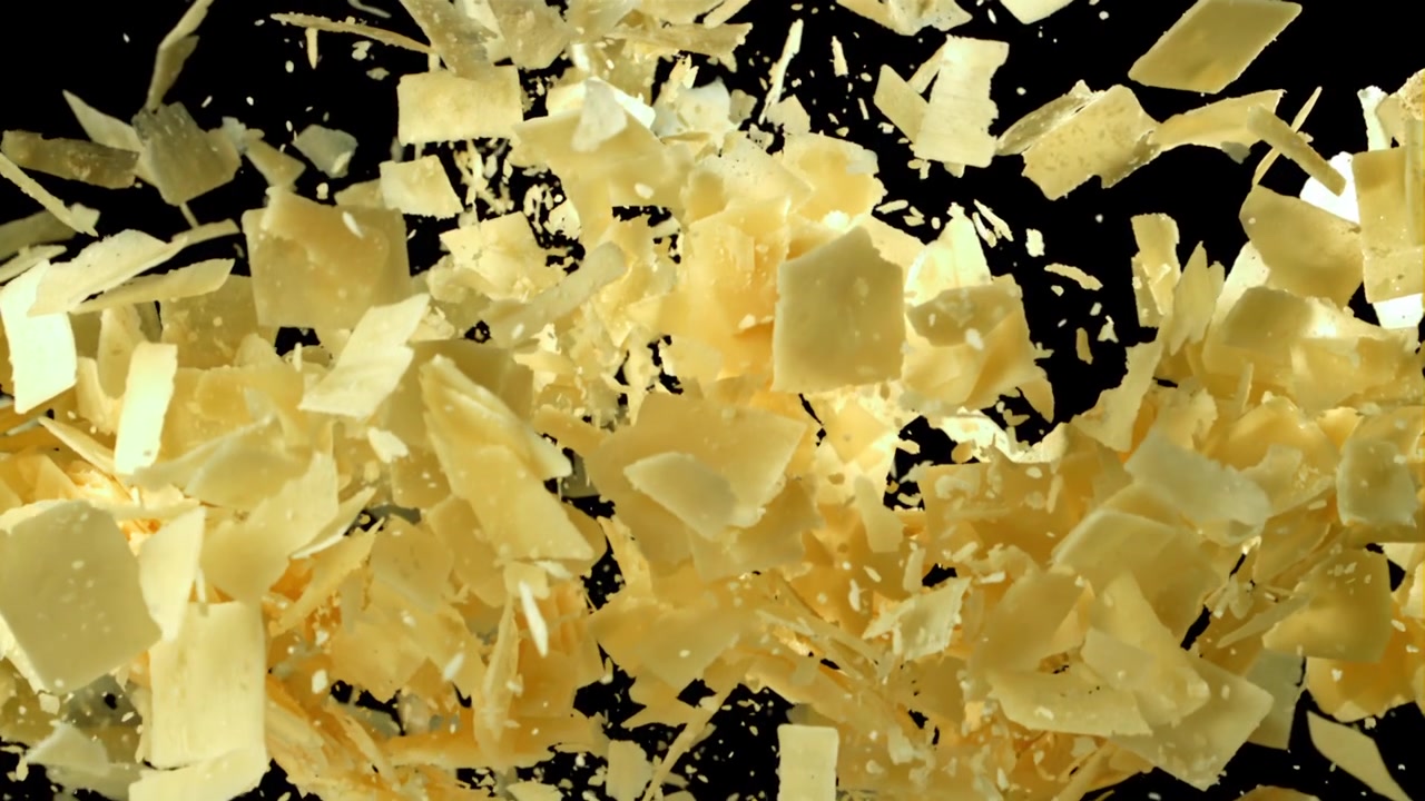 Slow Motion Explosion of Parmesan Cheese Flakes on Black Background