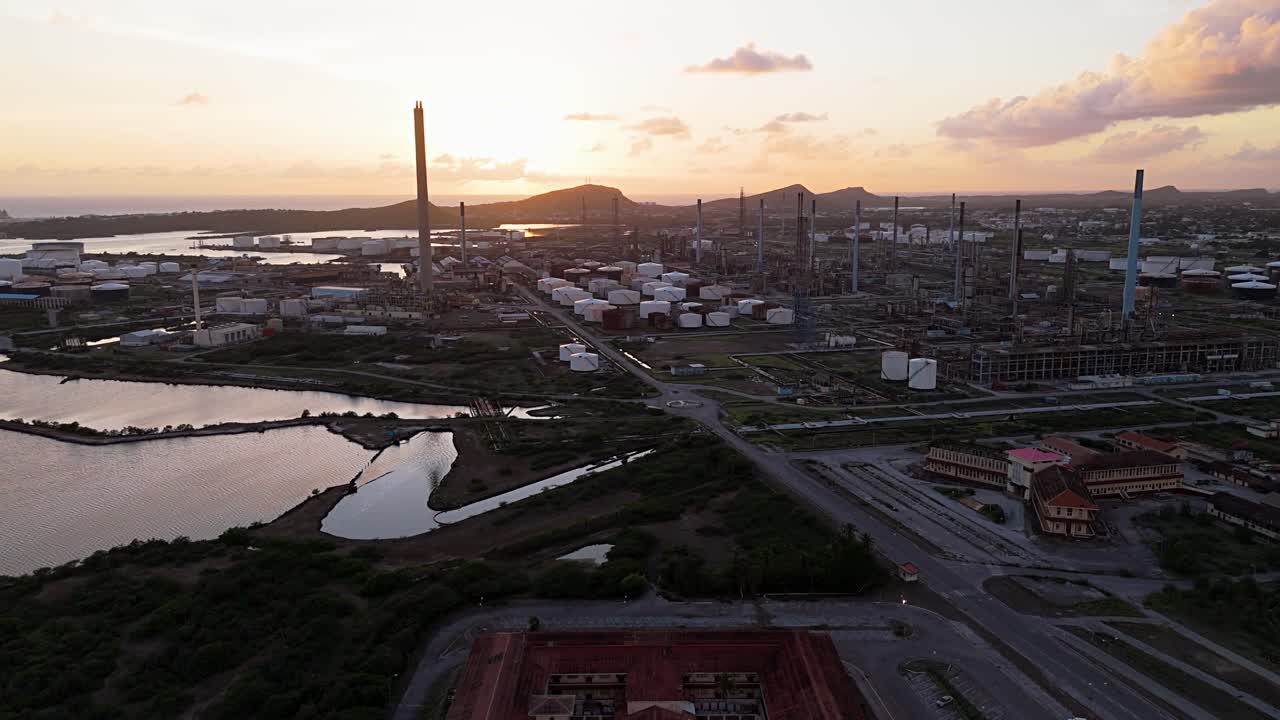 panorâmica aérea estabelecendo uma visão geral das estacas da refinaria de petróleo ao pôr-do-sol