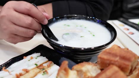 person eating congee with deep-fried dough sticks