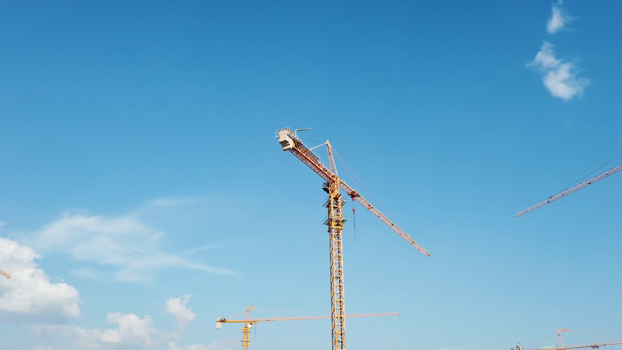 Panning shot of high rise construction with cranes and blue sky with nice weather and clouds out in the open during daytime