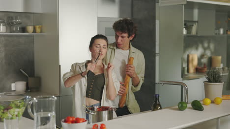 joyful couple dancing and singing while cooking in a modern kitchen