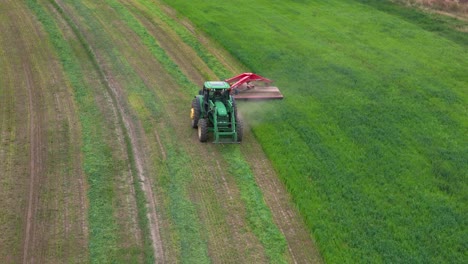 symmetry in action: aerial scene of a green tractor mowing hay in british columbia