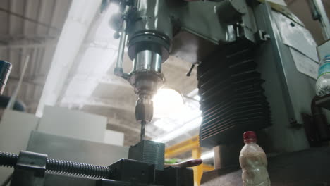 Low-angle-of-a-big-industry-drilling-machine-working-on-a-piece-of-metal-in-slow-motion