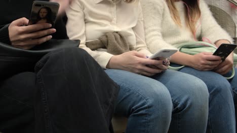 people using smartphones on a subway train