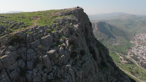 aerial view revealing a person on top of mount arbel, in sunny israel - tilt, drone shot