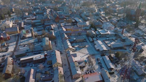 aerial establishing view of kuldiga old town , houses with red roof tiles, sunny winter day, travel destination, wide drone shot moving backward, tilt up