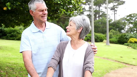 Retired-couple-standing-in-the-park-together-with-woman-on-a-bike