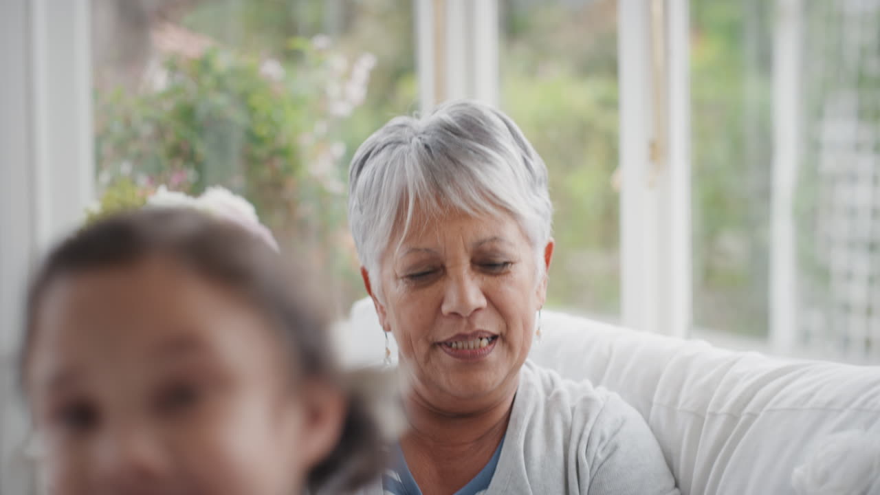 귀여운 작은 소녀가 할머니를  ⁇ 안고 미소 짓고 손녀를  ⁇ 안고 행복한 할머니가 집에서 손녀의  ⁇ 안기를 즐기고 있습니다. 가족 개념 4k