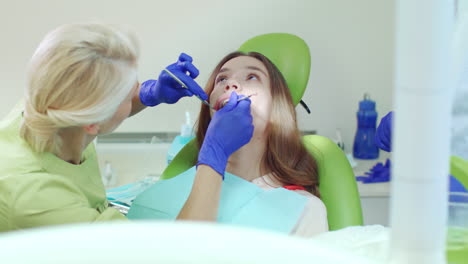 dentist examining patient teeth with mouth mirror and dental probe