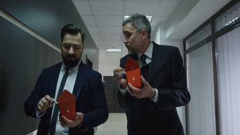 Businessmen Chatting and Eating in Office Corridor. Medium shot of businessmen chatting and eating chinese food in office corridor
