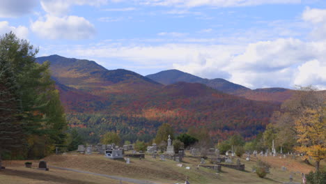 Ein-Friedlicher-Friedhof-Mit-Majestätischen-Bergen,-Die-Im-Hintergrund-Mit-Herbstlaub-Bedeckt-Sind,-Statische-Aufnahme