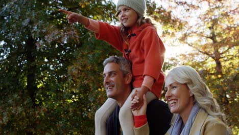 girl on dads back with mom walking outdoors