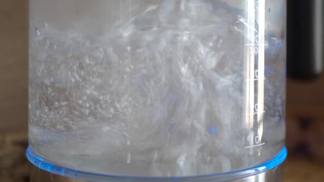 青い光が灯るガラス製電気ケトルで沸騰する水のクローズアップ