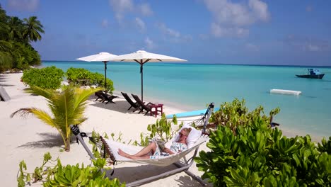 tropical maldives scene, pull back revealing beautiful woman relaxing on beach hammock at secluded resort, 4k