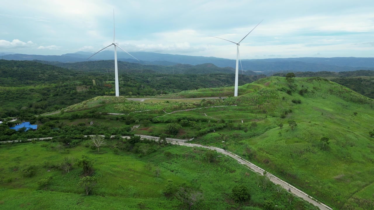 Vista aerea panoramica delle turbine eoliche filippine su verdi colline a Pililla, Rizal, di giorno, con uno sfondo montuoso tropicale.