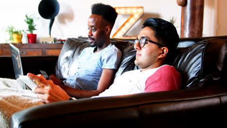 Man-using-digital-tablet-while-friend-doing-online-shopping-on-laptop