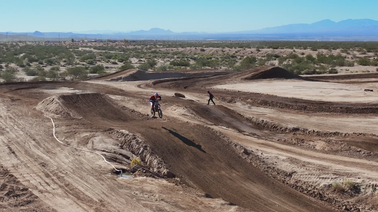 motociclista en una pista de tierra haciendo saltos altos - cámara lenta aérea