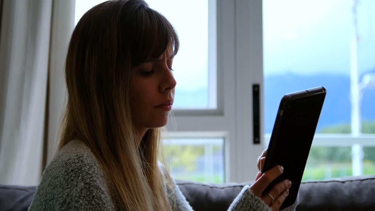 mujer usando tableta digital en el sofá 4k