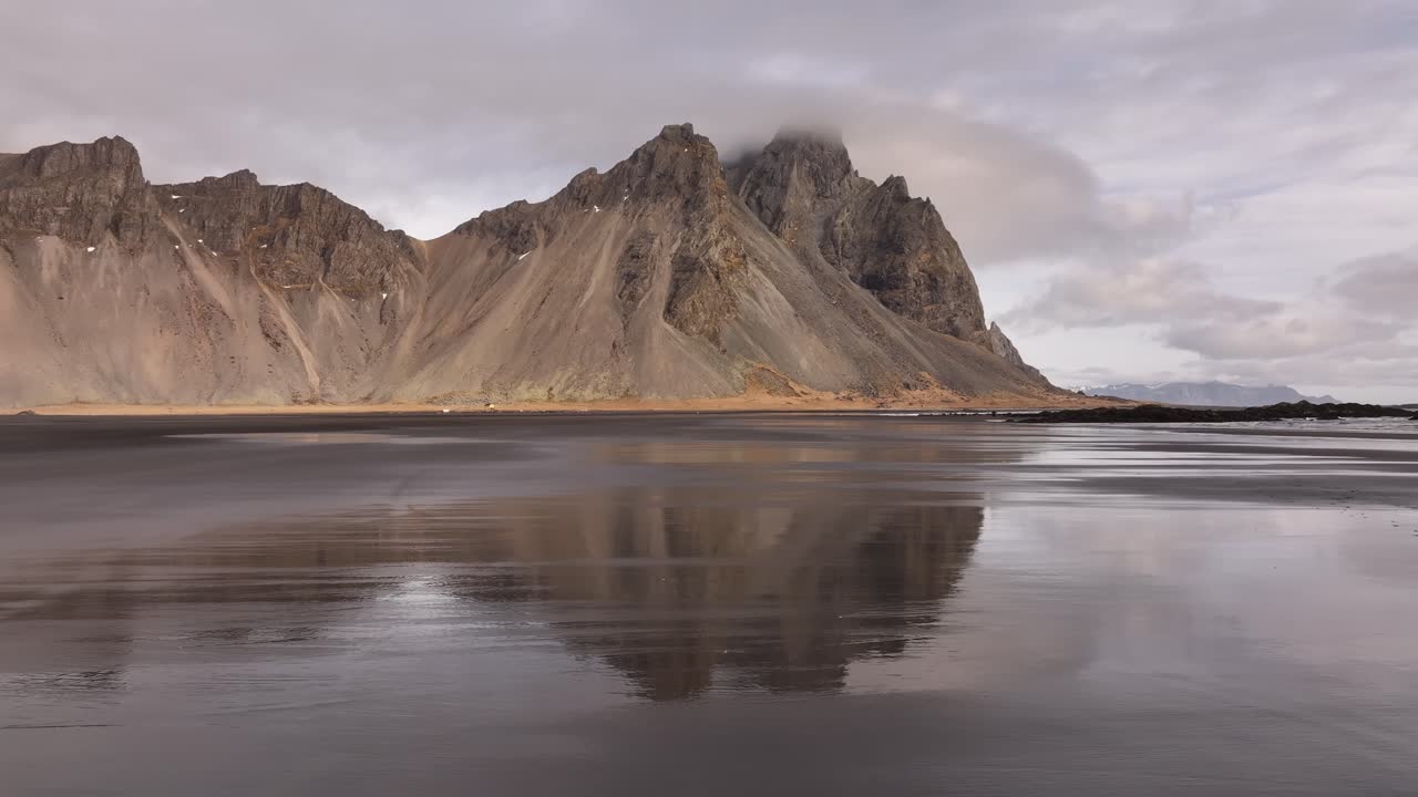 Tågede tinder af Vestrahorn afspejlet i sort sandstrand, Stokksnes, Island