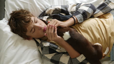 teenager cuddling with a dog in bed