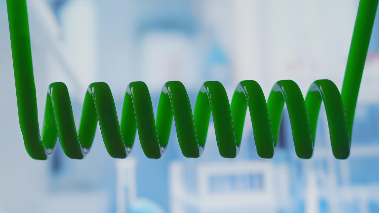 왼쪽에서 오른쪽으로 수평으로 회전하는 녹색 액체 과학 실험실 응축기 과학 실험실 실험 바이러스에 대한 백신 개발 인간 게 연구 고품질 4k 영상