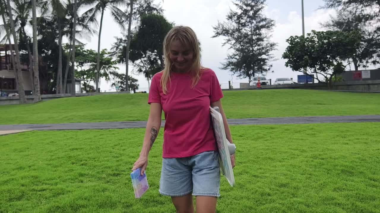 mujer en un parque junto a la playa sosteniendo una tabla
