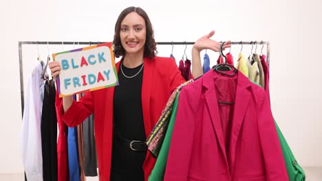 excited woman with 'black friday' sign and clothes on a rack