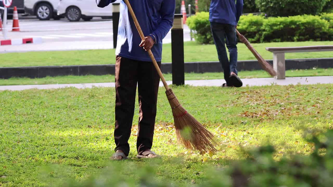 persona barriendo las hojas caídas en la hierba