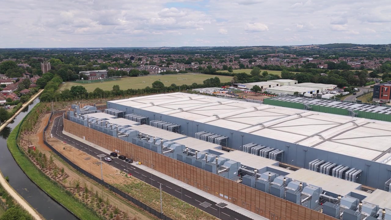 Complesso industriale di data center circondato da vegetazione e strade in una giornata luminosa in Europa, che mostra una massiccia infrastruttura per l'archiviazione cloud e la tecnologia di elaborazione server