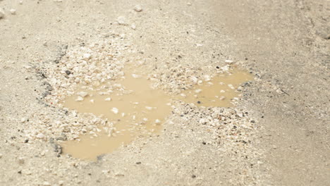 puddle holes on broken asphalt roads after rain at daytime in leiria, portugal