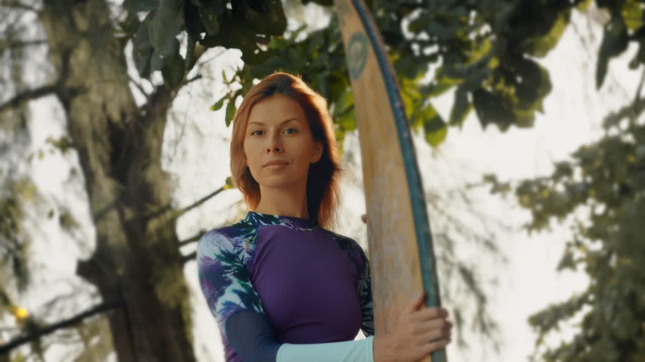 mujer con tabla de surf al atardecer