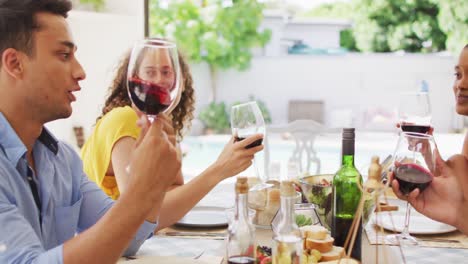 grupo de diversos amigos masculinos y femeninos riendo y bebiendo vino juntos en una fiesta de cena