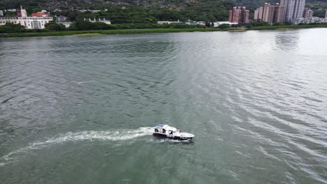 Fliegen-über-Den-Fluss-Mit-Einem-Kleinen-Boot,-Das-Durch-Das-Wasser-Fährt-Und-Wellenzüge-Hinterlässt