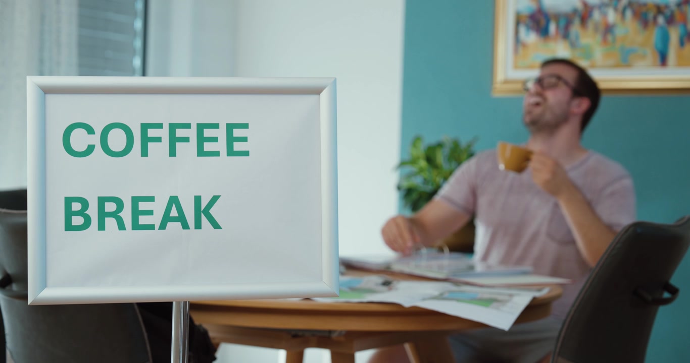 Mand nyder en kop kaffe under en arbejdsfrokost, repræsenterende afslapning, arbejdsrutine, hvile, forfriskning og en pause fra arbejdet.