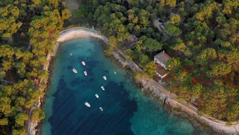 Flyover-shot-of-a-small-cove-protecting-a-group-of-anchored-motorboats-in-Losinj,-Croatia