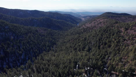 Aerial-view-of-a-New-Mexico-mountain-valley-pulls-back-and-tilts-to-reveal-a-distant-horizon