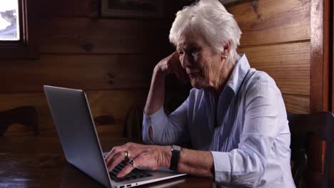 woman with hand on face using laptop at home 4k